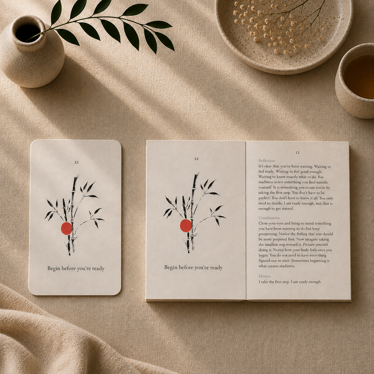 The Kokū Begin before you're ready card beside the open Pocket Book on beige fabric, each showing a hand-painted bamboo illustration with a vermilion dot.